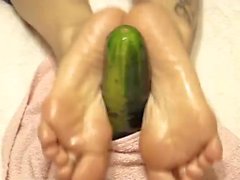 Oiled soles stroking a cucumber